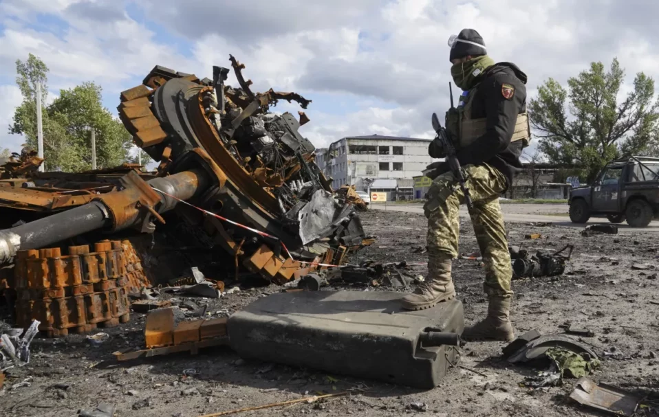 A Ukrainian soldier stands near pieces of a Russian tank Tuesday in the Kharkiv region.(Andrii Marienko / Associated Press)